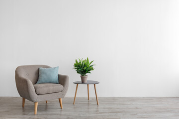 Retro armchair with pillow, plant in pot on table on gray wall background in living room, domestic...