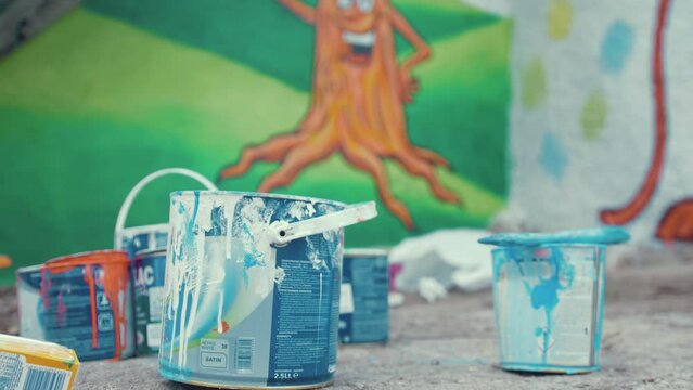 Paint tins rack focus to childrens playground mural cartoon tree