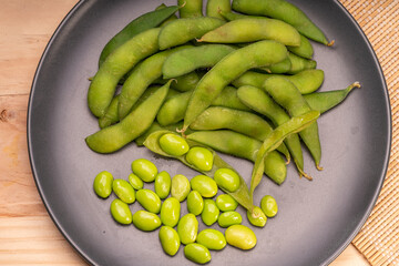 Edamame,boiled green soybeans or Edamame bean served in a black  plate on wooden background