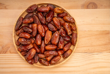 Dried date palm fruit on a wooden plate, date palm fruit with leaf on wooden background