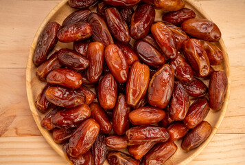 Dried date palm fruit on a wooden plate, date palm fruit with leaf on wooden background