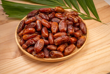 Dried date palm fruit on a wooden plate, date palm fruit with leaf on wooden background