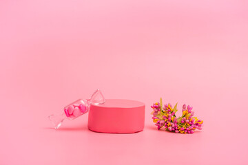 Pink podium for cosmetics or products with flowers and hearts on a pink background. Holiday card, closeup copy space
