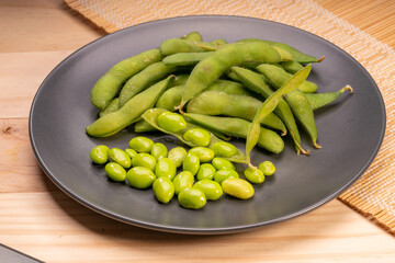 Edamame,boiled green soybeans or Edamame bean served in a black  plate on wooden background