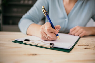 close-up of a woman's hand with a pen makes a plan on paper. Checklist