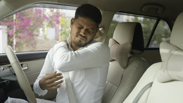 Tired young indian cab driver suffering from joint pain due to over driving - concept of arthritis, unhealthy lifestyle, overworked and exhusted.