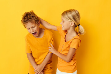 Portrait of cute children in yellow t-shirts standing side by side childhood emotions yellow background unaltered