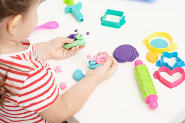 baby girl playing with plasticine, sculpting figures snails, home educational games, colorful play dough