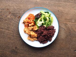 balanced and healthy dish of riceberry, broccoli, kimchi and fried chicken