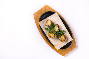 Baked stuffed mushrooms with mushrooms, cheese and herbs, on a wooden board on a white isolated...