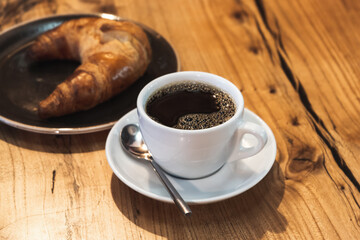 Black coffee with croissant. White cup of filter coffee