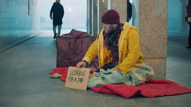 A beggar is informing passers-by that he is looking for a job