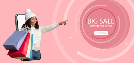 Online shopping. Young black woman holding shopper bags, offering big sale, coming out of mobile phone screen