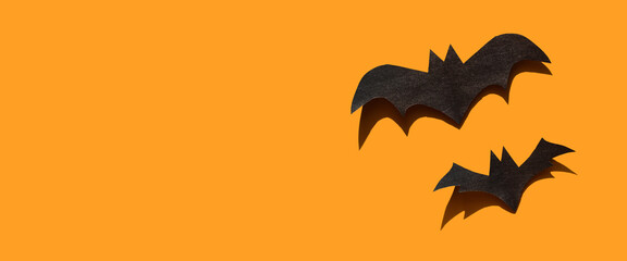 Halloween decorations with two bats on orange background. Holiday party, minimal greeting card, spooky concept. flat lay, copy space, top view, place for text, banner