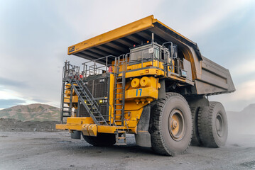 A heavy dump truck drives through an open pit mine.
