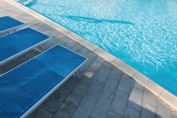 Beautiful blue swimming pool with sun loungers on a sunny warm summer day. Holidays and rest