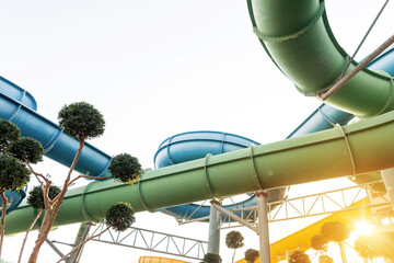 Summer aqua park with slides and colorful pipes at sunset. Sunny rest