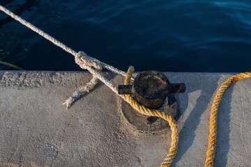 yacht boat is moored with a rope to the bollard in a port at sunset. Stop at the dock. Anchor and brake concept