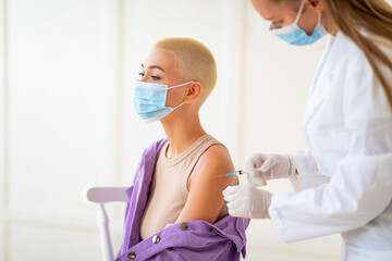 Immunization and health care. Young lady getting vaccinated against coronavirus. Stop coronavirus,...