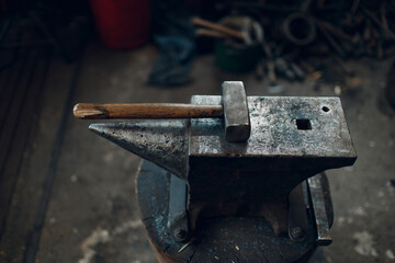 Blacksmith's hammer on metal anvil at forge. Overhead view