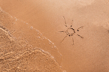 Drawn sun on the sand with a sea wave. Summer vacation concept. Warm holidays. Clear water on yellow sandy beach
