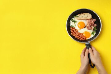 Female hands hold pan with breakfast on yellow background