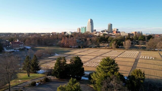 aerial push in to winston salem nc, north carolina skyline with god's acre in foreground
