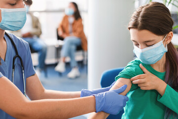 Girl Getting Vaccinated Against Covid-19, Female Doctor Applying Plaster - obrazy, fototapety, plakaty