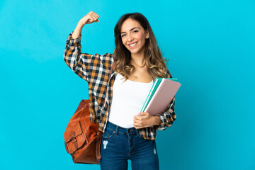 Young student woman isolated on blue background doing strong gesture