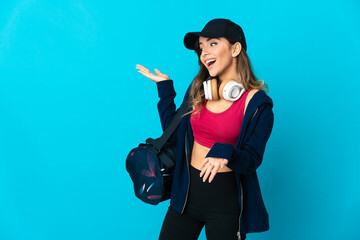 Young sport woman with sport bag isolated on blue background with surprise expression while looking side