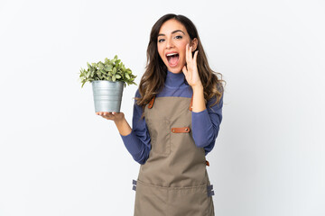 Gardener girl holding a plant isolated on white background shouting with mouth wide open