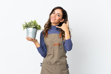 Gardener girl holding a plant isolated on white background making phone gesture. Call me back sign