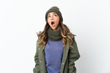 Young girl with winter hat isolated on white background looking up and with surprised expression
