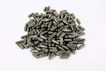 A pile of black medicine or health supplement pills on white background
