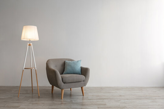 Retro Armchair With Blue Pillow, Glowing Lamp On Floor On Gray Wall Background In Office Or Living Room