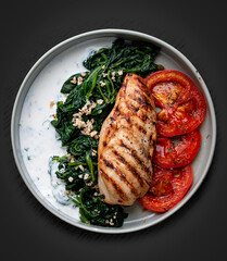 Fried chicken fillet with Greek dzadziki sauce and stewed spinach. Top view