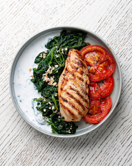 Fried chicken fillet with Greek dzadziki sauce and stewed spinach. Top view