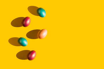 Happy Easter holiday concept. Set of handmade colorful eggs isolated on yellow background with shadow. Simple trendy minimal composition, flat lay, top view, copy space, place for text, banner