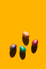 Happy Easter holiday concept. Set of handmade colorful eggs isolated on yellow background with shadow. Simple trendy minimal composition, flat lay, top view, copy space, place for text, banner