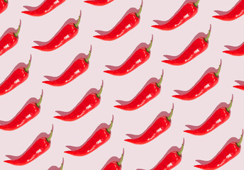 Pattern out of red peppers on a pink background. Minimal concept.