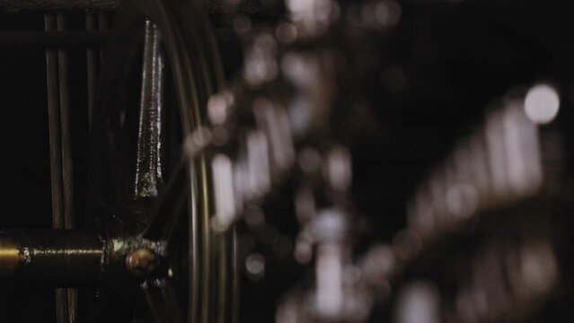 Close view of elevator switchgear with blurred view of a spinning wheel in the background of a manual elevator.