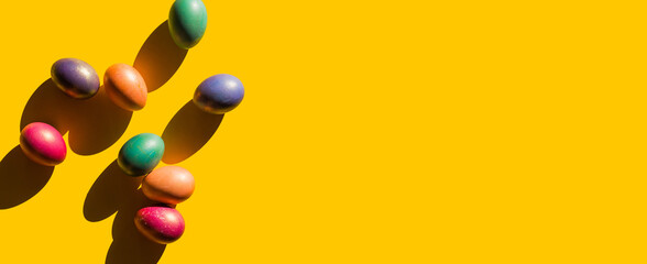 Happy Easter holiday concept. Set of handmade colorful eggs isolated on yellow background with shadow. Simple trendy minimal composition, flat lay, top view, copy space, place for text, banner