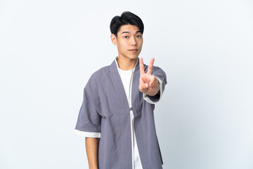 Young Chinese man isolated on white background smiling and showing victory sign