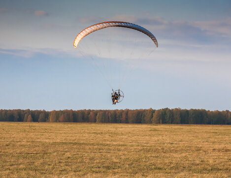 Paraglider on the background of blue sky with white clouds and fields in summer