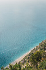 Above view to a dreamy beach with coastline and crystal emerald water on a beautiful sunny summer day. Seascape with clean blue water. Vacation travel concept.   