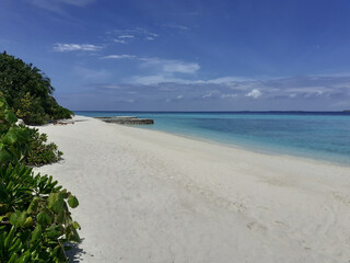 A paradise tropical island with the white sand beach near the turquoise ocean. Summer vacation in Maldives.