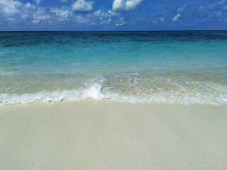 A beach with the white sand near the turquoise ocean. Clear skyline. Maldives, tropical paradise.