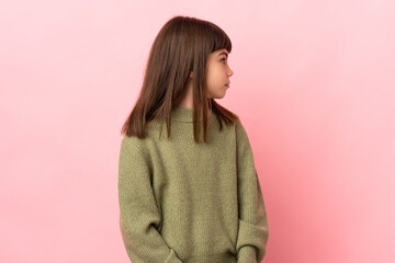 Little girl isolated on pink background looking to the side