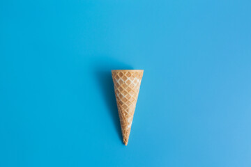 Sweet crispy empty waffle cup ice cream cone on blue background
