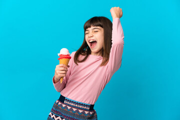Little girl with a cornet ice cream isolated on blue background celebrating a victory